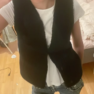 Svart pälsväst från GAP  - Säljer en mörk blå/ marinblå super fin pälsväst från GAP kids. Västen är ärmlös och har en klassisk, rak passform utan synliga knappar eller dragkedja. Perfekt att styla över en t-shirt eller skjorta för en trendig look. Hör av dig om du har frågor eller funderingar 💕