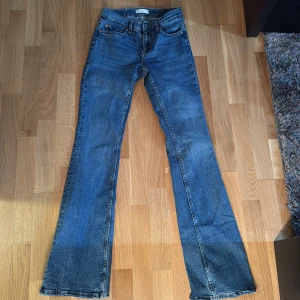Blå bootcut jeans från Perfect Jeans - Säljer ett par klassiska blå bootcut jeans från Perfect Jeans i storlek 34. Jeansen har normal passform, klassisk femficksdesign och är tillverkade i denim. Perfekta för dig som gillar en tidlös stil med lite utsvängda ben. Nya 