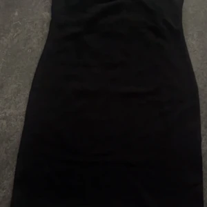 Svart tight klänning från H&M - En klassisk svart tight klänning från H&M. Klänningen är ärmlös och har en enkel, stilren design som passar perfekt till olika tillfällen. Materialet är mjukt och följsamt för en bekväm passform.