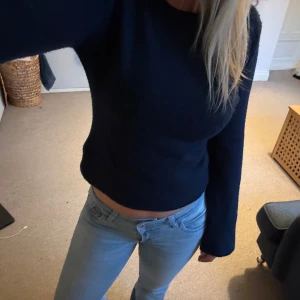 Mörkblå croppad stickad tröja - Säljer en mörkblå croppad stickad tröja med lång ärm och rund halsringning. Tröjan har en enkel och stilren design som passar perfekt till jeans eller kjol💘