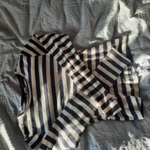 Randig ribbad långärmad tröja - Säljer en ribbad långärmad tröja med marinblå och vita ränder. Tröjan har en klassisk rund halsringning och är figurnära i modellen. Perfekt för dig som gillar en stilren och tidlös look med lite edge.