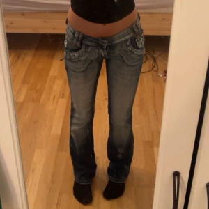 Lågmidjade bootcut jeans från Fornarina - Säljer ett par y2k vintage lågmidjade bootcut jeans från  med slitningar och snygga detaljer på fickorna. Jeansen har en unik design och söm samt dragkedjor på bakfickorna! Midjemått 33 cm tvärsöver, perfekt längd för någon runt 160-165 cm lång, inga defekter. 