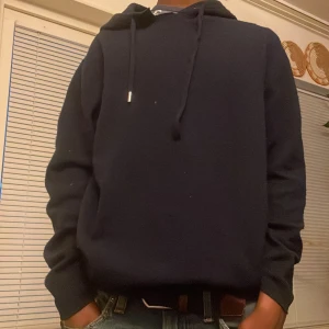 Mörkblå hoodie med huva och snörning - Säljer en stilren Kashmir hoddiemed huva och snörning. Tröjan har en klassisk passform och är långärmad, perfekt för kyligare dagar. Materialet känns mjukt och bekvämt, och den funkar lika bra till jeans som till mjukisbyxor.