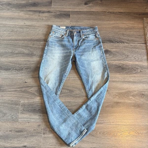 Levi's ljusblå jeans straight fit - Klassiska Levi's jeans i blå tvätt med raka ben och normal passform. Jeansen har fem fickor, knappgylf och den ikoniska läderpatchen bak i midjan. Tillverkade i slitstarkt bomullsjeans, perfekt för en avslappnad och tidlös stil. Jeansen är i jätte bra skick och i storlek 28/30! Hör av er vid frågor och funderingar, pris tål att diskutera