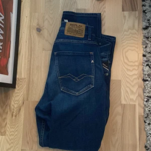Blå jeans från Replay, storlek 32/30 - Snygga blå jeans från Replay med klassisk femficksdesign och diskret logga på bakfickan. Jeansen har normal passform och är tillverkade i slitstarkt denimtyg. Perfekta för dig som gillar stilrena och tidlösa jeans. Nypris: 1850