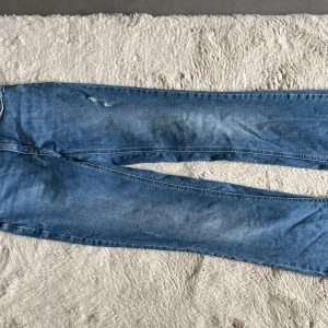 Blå jeans från Vero Moda - Säljer ett par klassiska blå jeans från Vero Moda med raka ben och normal passform. Jeansen har två bakfickor och subtila slitningar framtill för en avslappnad look. Perfekta till vardags och lätta att matcha med olika toppar. ANVÄNDA MEN I SUPER GOTT SKICK, MIDWAIST, SUPER SKÖNA!!