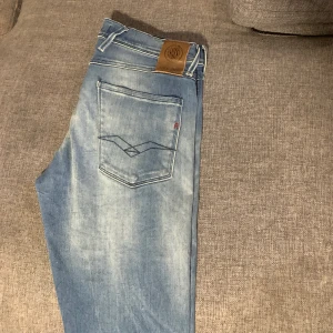 Replay Anbass ljusblå jeans - Säljer ett par Replay Anbass jeans i ljusblå tvätt med slitningar. Klassisk femficksmodell med läderpatch bak i midjan och raka ben. Perfekta för en avslappnad stil. Helt nya! Sällsynta!🔥