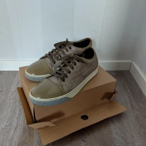 Lanvin cap toe  - Säljer ett par snygga Lanvins!fint skick som på bilderna. Perfekt för dig som gillar old money! Krokodilmönstrat skinn och rund tå. Skorna har snörning och en vit platt sula. Perfekta för dig som vill ha något stilrent och unikt. Priset är ej hugget i sten! Fraktar alltid samma dag! 