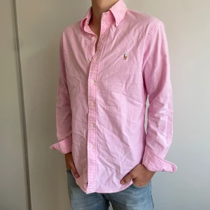 Rosa skjorta från Ralph Lauren - Säljer en klassisk rosa skjorta från Ralph Lauren med broderad logga på bröstet. Skjortan är perfekt inför sommaren och är i helt nytt skick bara använd ungefär vid 2 tillfällen✅☀️ det är bara att skriva om du har några funderingar🤩nypris:1200kr mitt pris:449kr