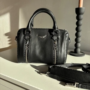 Zadig&Voltaire sunny väska - Snygg svart handväska i skinn från Zadig&Voltaire. Modellen är Sunny och nypris är 4245. Axelrem medföljer samt dess egna dustbag! Väldigt sparsamt använd, inga defekter!