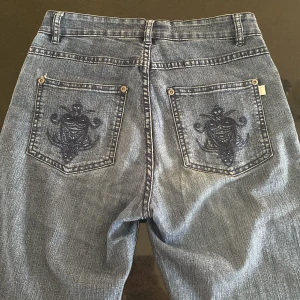 Blå jeans med broderade bakfickor - Blå jeans med raka ben och snygga broderade detaljer på bakfickorna. Innerbenslängd: 79 cm. 