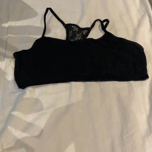 Svart spets bralette från beTEEN - Svart bralette med tunna axelband och spetsdetaljer från beTEEN. Toppen har en dekorativ spets i ryggen och är tillverkad i ett mjukt material som känns bekvämt mot huden. Perfekt för dig som vill ha en enkel men snygg topp.
