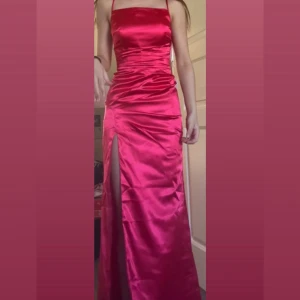 Röd/Rosa balklänning - Enbart testad❗️Säljer en superfin balklänning med satinmaterial, smala axelband, hög slits och snygg snörning i ryggen. Klänningen ser lite röd ut på bilder, men den är mer rosa i verkligheten. 🩷Klänningen har figurnära passform och är perfekt för bal. 🩷Jag är 165cm och den är perfekt längd med 5-10cm klackar. Klänningen är enbart testad, jag säljer den då jag valde en annan. Lapparna sitter kvar🩷 Jag kan mötas i Halmstad eller posta. Köparen står för frakt och jag står inte för postens slarv🩷