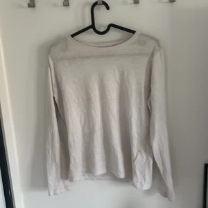 Vit långärmad tröja från 157 - En enkel och stilren vit långärmad tröja från 157, tillverkad i 100% bomull. Perfekt basplagg med rund halsringning och rak passform. Passar till många olika outfits och är skön att bära.