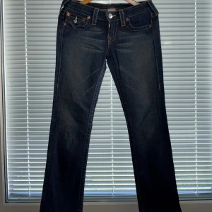 Mörkblå jeans från True Religion - Ett par äkta True Religion mörkblå jeans. Snygga bakfickor med klassiska True Religion detaljer. Jeansen är i fint sick och passar både till vardags eller för att klä upp med en festtopp!! 💕 {Längd:93cm, Innerbenslängd: 71cm}