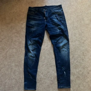 Mörkblå jeans med färgstänk från Dsquared2 - Säljer ett par riktigt feta mörkblå jeans från Dsquared2, läderpatch bak och smal passform. Perfekta nu till sommaren! Storlek 34