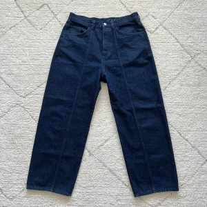 Mörkblå jeansbyxor från COS - Säljer ett par mörkblå jeansbyxor från COS i relaxed fit. Byxorna har raka ben, klassiska fem fickor och hög midja. Materialet är kraftig denim och passformen är avslappnad med en modern siluett.