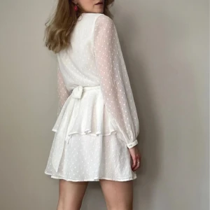 Vit student klännning från Gina Tricot - Fin avslutnings klänning från Gina Tricot med omlottmodell och volangdetaljer. 