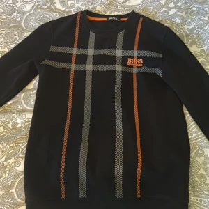 Svart tröja med rutigt mönster från BOSS - Boss tröja som är köpt utomlands, det står S men passar en som är ca 158 -170 beroende på hur man vill att den ska sitta . 