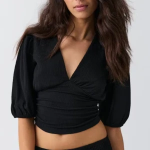 Svart omlottopp med puffärm från Gina Tricot - Säljer en svart omlottopp från Gina Tricot med v-ringning och puffiga trekvartsärmar. Toppen är i storlek M 