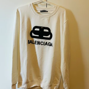 Vit sweatshirt från BB - Vit sweatshirt med svart logotyp och tryck framtill. Tröjan har rund halsringning och långa ärmar. Perfekt för en stilren och trendig look.