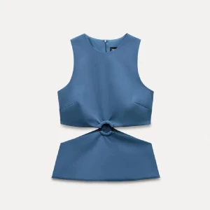 Blå ärmlös croppad topp med ringdetalj - Säljer en blå ärmlös topp med unik ringdetalj framtill som skapar en cool cut-out effekt. Toppen har rund hals och dragkedja i ryggen. Perfekt för dig som vill sticka ut med en trendig och modern look.