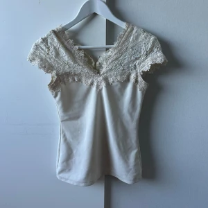 Vit spetsdetaljerad topp med v-ringning - Säljer en väldigt fin topp men som tyvärr aldrig kom till användning, det är bara att skriva ifall ni skulle undra över något🥰