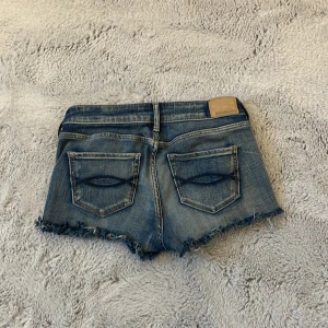 Jeansshorts från Abercrombie & Fitch - Snygga blå jeansshorts från Abercrombie & Fitch med fransig kant och klassiska bakfickor. Modellen har låg midja. Så snygga till sommaren🩷säljer då dom är lite stora på mig, dom är lågmidjade(sista bilden)💗Priset går troligtvis att diskuteras🙌🏼❤️