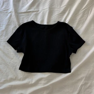 Svart croppad t-shirt - Säljer min svarta fina kroppade T-shirt, använd ett fåtal gånger så i väldigt bra skick! 🌟🌟 Lapparna är bortklippta men det passar XS/S, stretchig också.