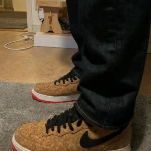 Nike Air Force 1 cork - Säljer ett par unika Nike Air Force 1 med korkmönstrad ovandel, svart swoosh och svarta skosnören. Skorna har vit sula med röd undersida och klassisk Air-detalj. Endast testade, köpa för cirka 5500