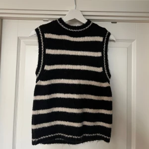 Svart och vit stickad väst med ränder från Zara - Säljer en stickad väst i svart och vitt med breda horisontella ränder. Västen har en hög, rund halsringning och är ärmlös. 