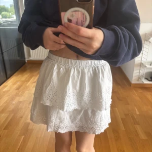 Vit volangkjol från Zara - Superfin vit kjol från Zara med två lager volanger och broderade detaljer. Kjolen har resår i midjan och är perfekt för sommardagar. Lätt och luftig modell som ger en söt och fräsch look. Storlek 164, skulle säga att den motsvarar XS/S