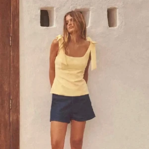 Gul linnetopp från zara - Snygg ljusgul linnetopp med breda axelband som knyts upptill. Perfekt för varma dagar och enkel att matcha med shorts eller kjol.
