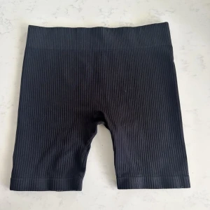 Svarta ribbade cykelshorts - Svarta cykelshorts med ribbad struktur och hög midja. Stretchigt material som sitter tight och bekvämt. Perfekta för träning eller en avslappnad stil.