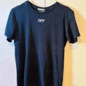 Svart t-shirt från Off-White - Säljer en svart t-shirt från Off-White med vit OFF-text på bröstet och stort grafiskt tryck med pilar på ryggen. Klassisk rund hals och korta ärmar. Perfekt för dig som gillar streetwear och vill sticka ut. Passar även för dem som har storlek S 