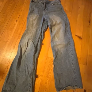 Blå jeansbyxor från Divided med råa benslut - Säljer ett par blå jeansbyxor från Divided med raka ben och råa, fransiga benslut. Klassisk femficksmodell och normal passform. Perfekta för en avslappnad och trendig look.