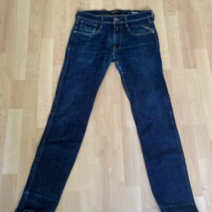 Mörkblå jeansbyxor från Replay Anbass - Säljer ett par mörkblå Replay Anbass jeans med klassisk femficksdesign och raka ben. Jeansen har snygga kontrastsömmar och normal passform. Perfekta för dig som gillar stilrena och tidlösa jeans.