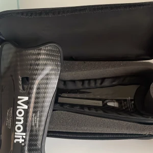 Monolit benskydd  - Säljer en svart väska från Monolit med Monolit benskydd, perfekta för den som utövar sporten. Väskan är avlång med dragkedja och har en slät yta. Passar bra för sportutrustning och är enkel att bära med sig. Benskydden är otroligt lätta och får det att knappt kännas när man har på sig de.