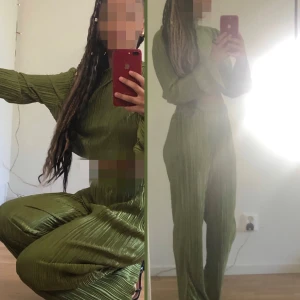 Plisserade gröna byxor med loose fit - Säljer ett par snygga plisserade byxor i olivgrönt med rak och loose passform. Byxorna har hög midja och är tillverkade i ett glansigt, lätt material som ger en cool och trendig look. Perfekta för dig som gillar statement-plagg och vill sticka ut.