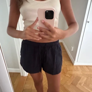 Marinblåa linneshorts  - Blå shorts i loose fit med elastisk midja och snörning framtill. Mjukt linnematrtial som känns mjukt och har fickor på sidorna. Perfekta för varma dagar.