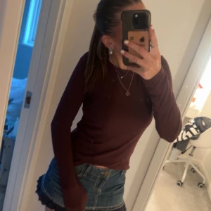 Mörkröd långärmad tröja - En enkel och stilren långärmad tröja i mörkröd färg. Tröjan har en tight passform och rund halsringning, perfekt att matcha med jeans eller kjol. Passar dig som gillar en clean och klassisk look.