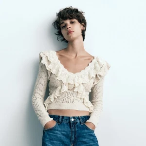 Beige stickad tröja med volang - Superfin beige stickad tröja med volangdetaljer och v-ringning. Den är croppad och har långa ärmar, vilket gör den både söt och trendig. Har inga tecken på användning, säljer då den inte längre kommer till användning 💕💕