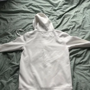 Vit hoodie från Polo Ralph Lauren - Säljer en clean vit hoodie från Polo Ralph Lauren i storlek M, lite liten i storleken så skulle rekommendera S. Tröjan har huva med snörning, dragkedja framtill och klassisk broderad logga på bröstet. Mjuk bomullskvalitet och fickor framtill. Perfekt för chill dagar eller när du vill ha en enkel men snygg look.