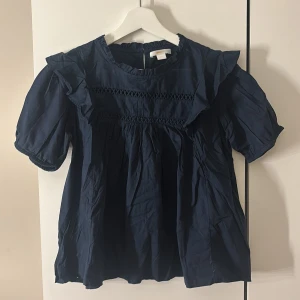 Mörkblå blus med volangdetaljer - Supersöt mörkblå blus med puffiga korta ärmar från gina Young. Säljer för att den inte kommer till andvändning längre den är i bra sick. Strycker och tvättar såklart den innan jag postar! Säljs inte längre, hör av er vid frågor eller intresse.