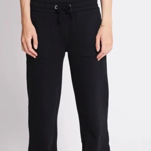 Svarta mjukisbyxor med snörning - Svarta mjukisbyxor med bred resår i midjan och snörning framtill. Byxorna har raka ben, stora fickor fram och bak samt är tillverkade i mjukt material. Perfekta för en chill och avslappnad look.