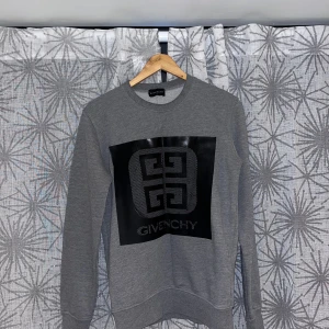 Grå sweatshirt från Givenchy - Snygg grå sweatshirt från Givenchy med stort svart logotryck på bröstet. Tröjan har rund hals, långa ärmar och ribbade muddar. Perfekt för dig som gillar stilrena designer och vill ha ett statement-plagg i garderoben.