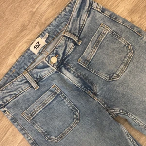 Bootcut jeans i ljusblå denim från 157 - Snygga bootcut jeans från 157 i ljusblå denim med klassiska fickor fram och bak. Jeansen har normal midja, bälteshällor och en lätt tvättad look. Perfekta för dig som gillar retrovibbar och en avslappnad stil.