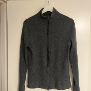 Grå merinoull kofta från These Glory Days - Säljer en stilren grå kofta från These Glory Days i mjuk superior merinoull. Det är en schysst fullzip som är perfekt för lager på lager. Nypris 1099