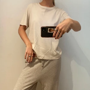 Vit basic t-shirt i bomull - En enkel och fräsch vit t-shirt med rund hals och korta ärmar. Modellen är normal i passningen och tillverkad i mjuk bomull, perfekt för en chill och clean look. Passar dig som gillar minimalistisk stil och vill ha en skön t-shirt till vardags.