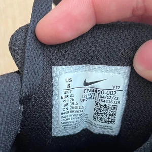 Nike Air Max 90 svart/vit sneaker - Säljer ett par klassiska Nike Air Max 90 sneakers i svart, grått och vitt. Skorna har en ikonisk siluett med mesh och syntetmaterial, vit swoosh och svart/vit sula med synlig Air Max-dämpning. Perfekta för dig som gillar streetstyle och sportig vibe.